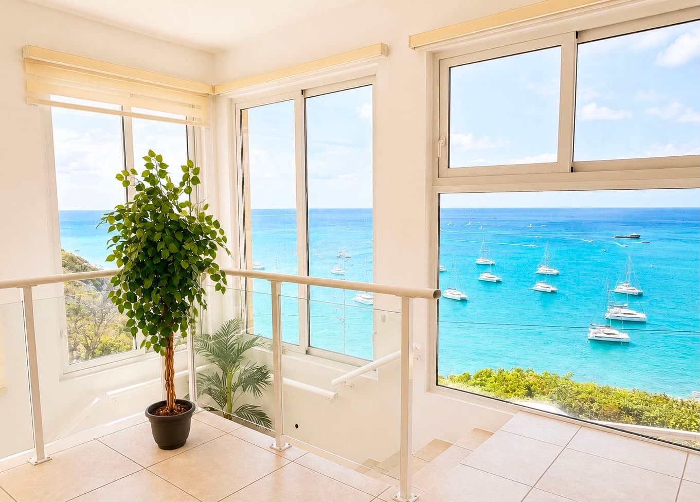 Bright indoor space with a potted plant and panoramic windows overlooking a tranquil blue sea and sailboats.