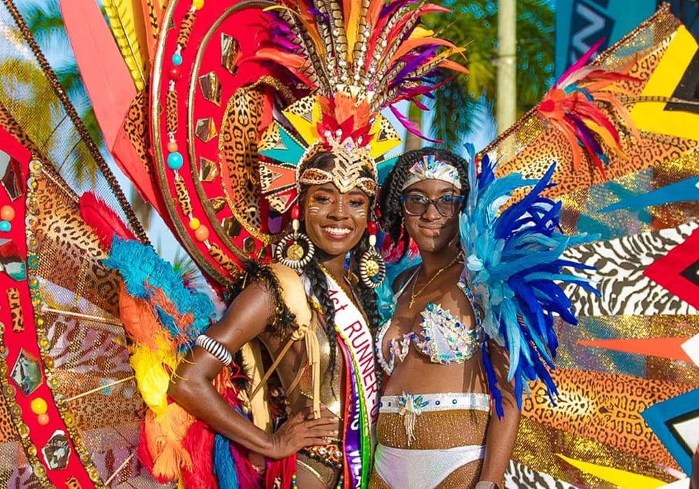 Two women in vibrant, colorful costumes pose together at a festive event.