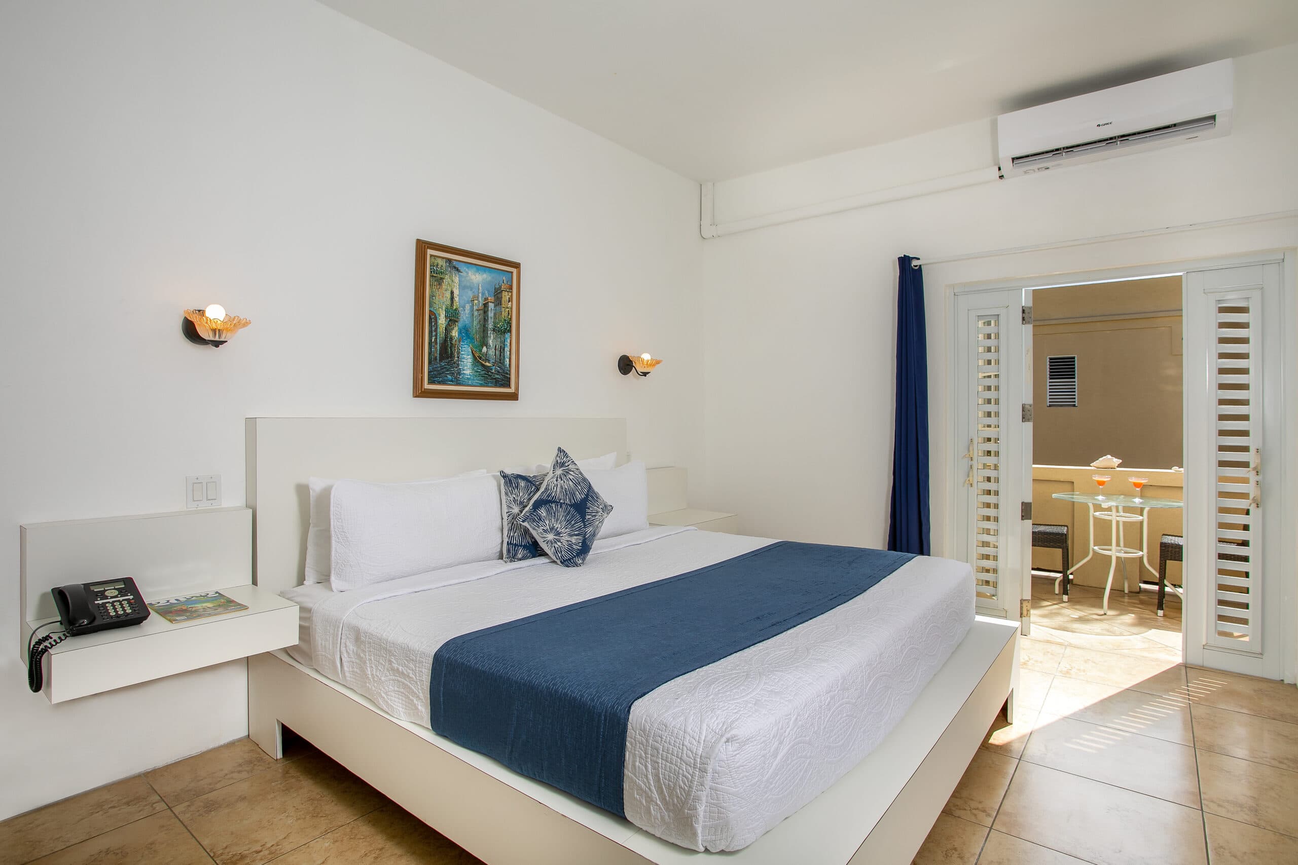 A modern hotel room featuring a queen-sized bed, artwork, and a patio door.