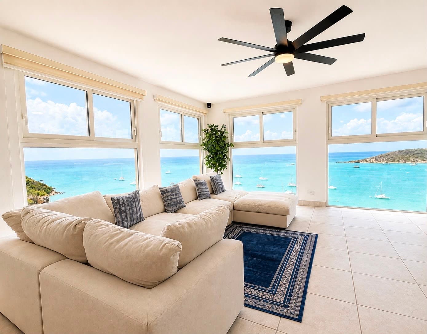 Bright living room with a couch, overlooking a blue ocean through large windows.