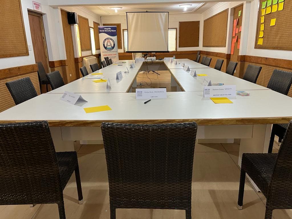 A large, empty conference room with a long table set for a meeting, featuring chairs and name cards.