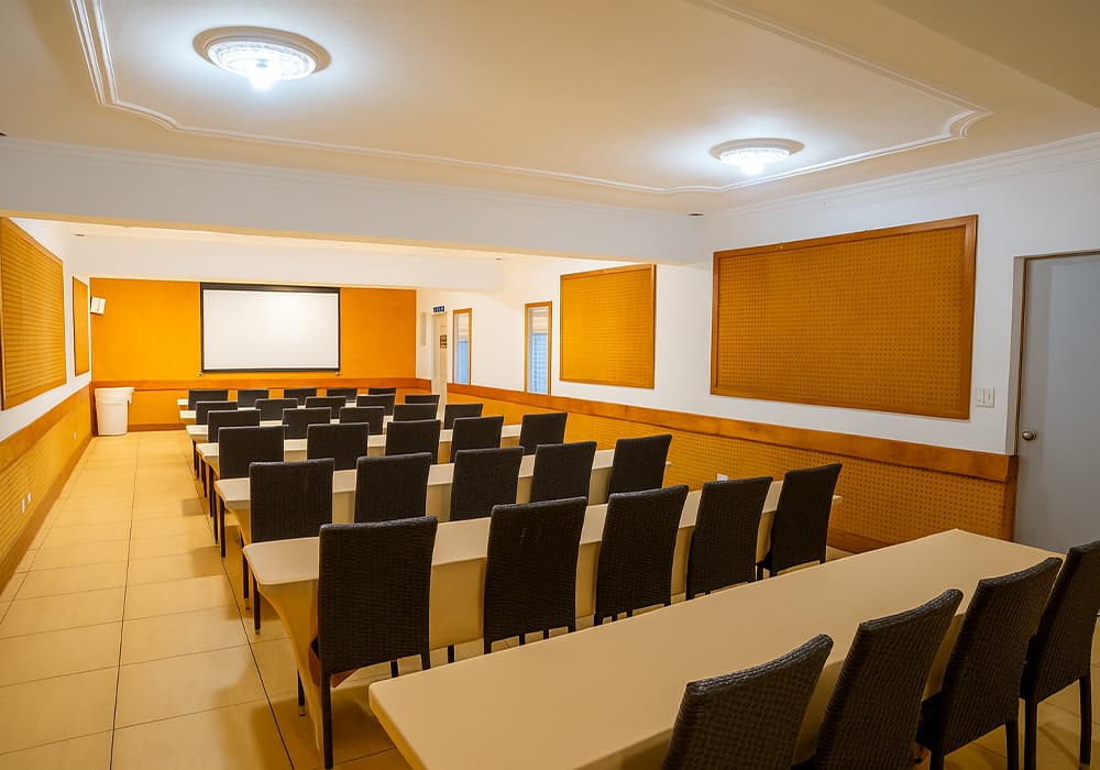 A spacious conference room with rows of chairs facing a screen.