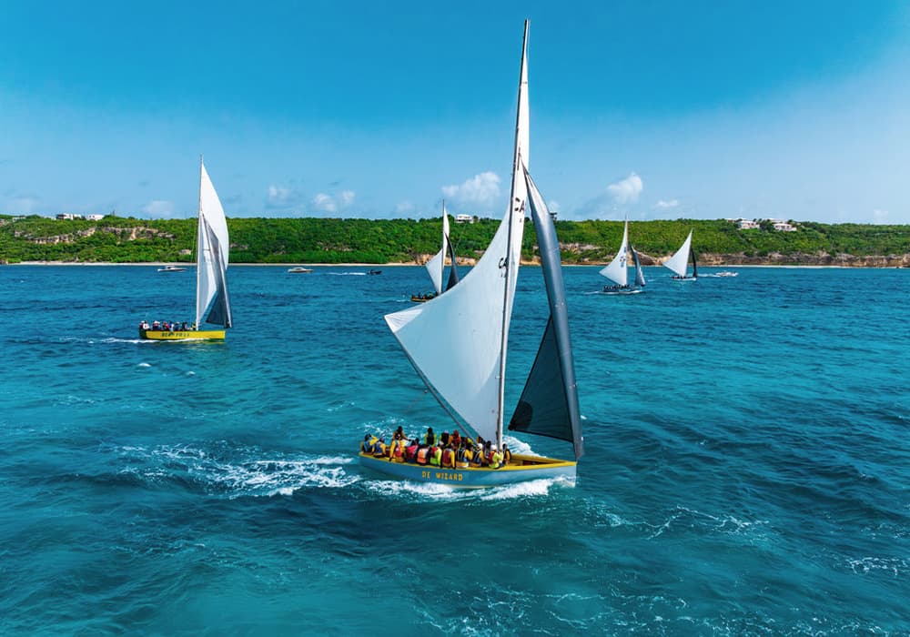 Sailboats navigate a turquoise sea under a clear blue sky.