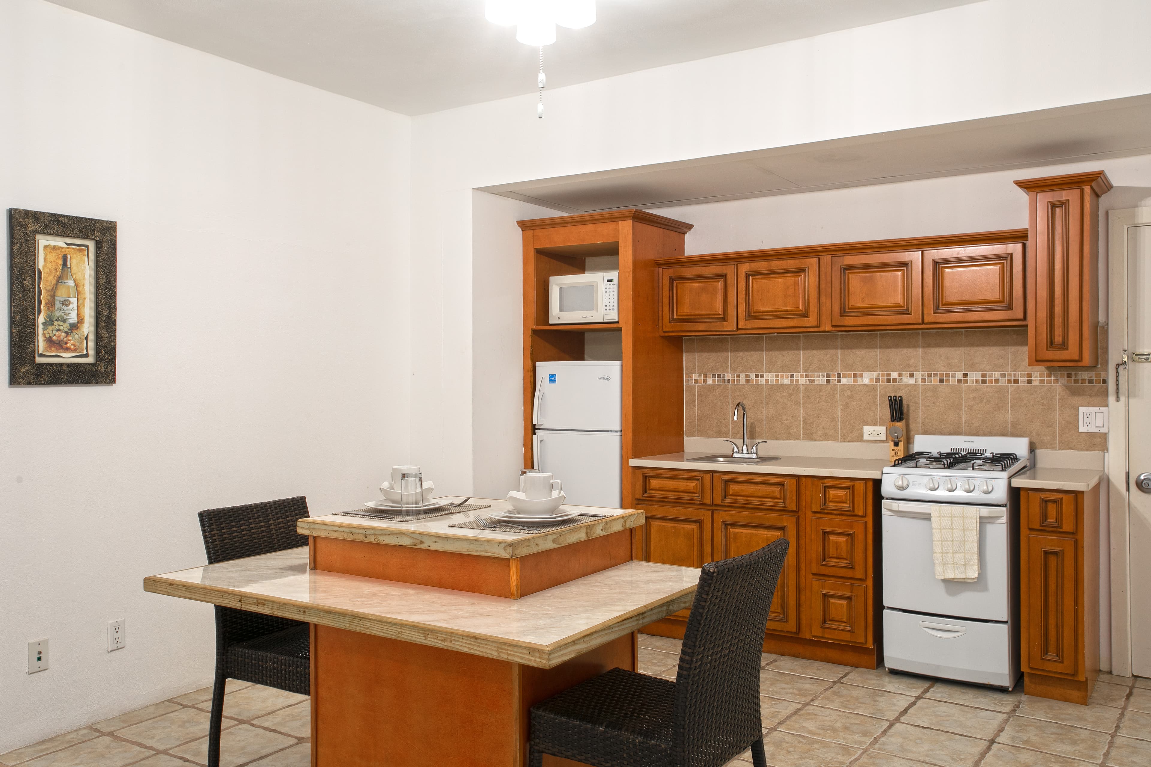 A cozy kitchen with wooden cabinets, a small dining table, and essential appliances.