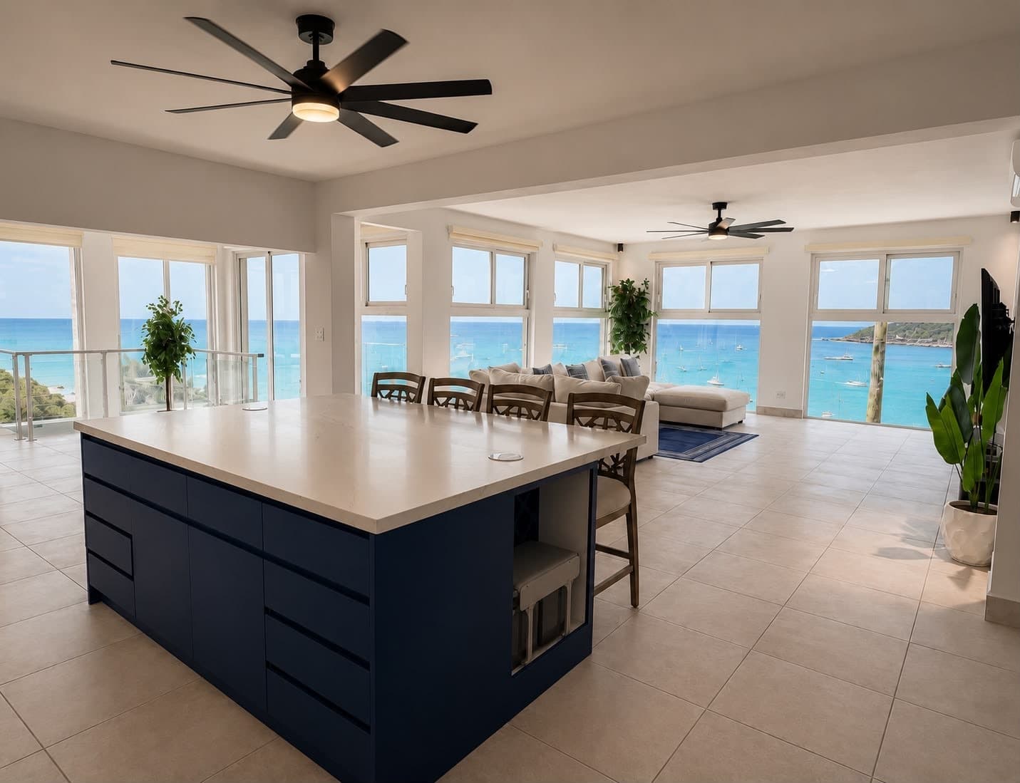 Modern kitchen with a blue island and panoramic ocean views through large windows.