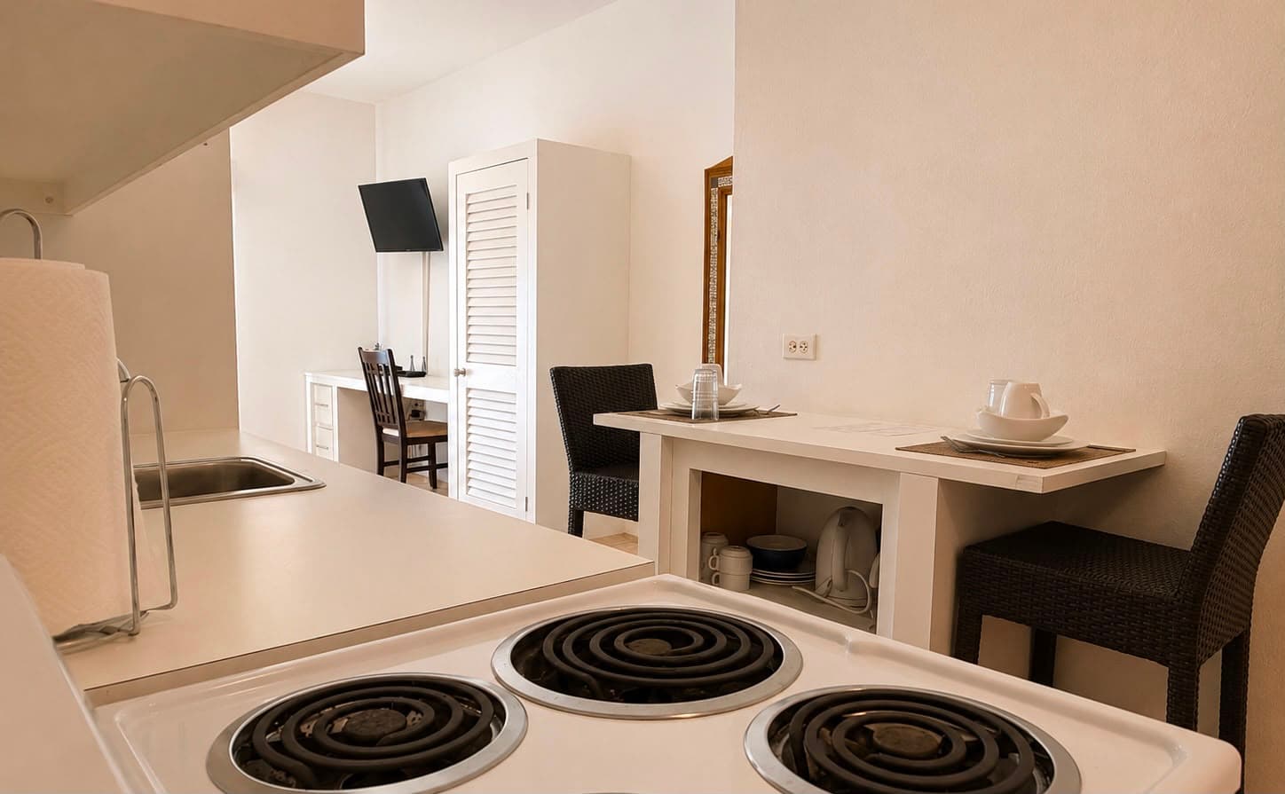 A modern kitchen with a stove, sink, and a small dining area.